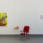 A red lawn chair by the white wall, with a painting to the left