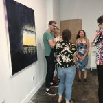 Patrons looking at paintings in the installation
