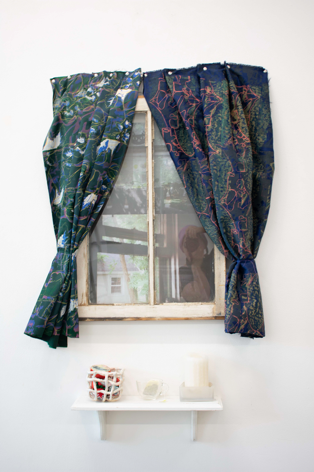 A small shelf beneath a window with curtains in the Headspace, Homebody installation