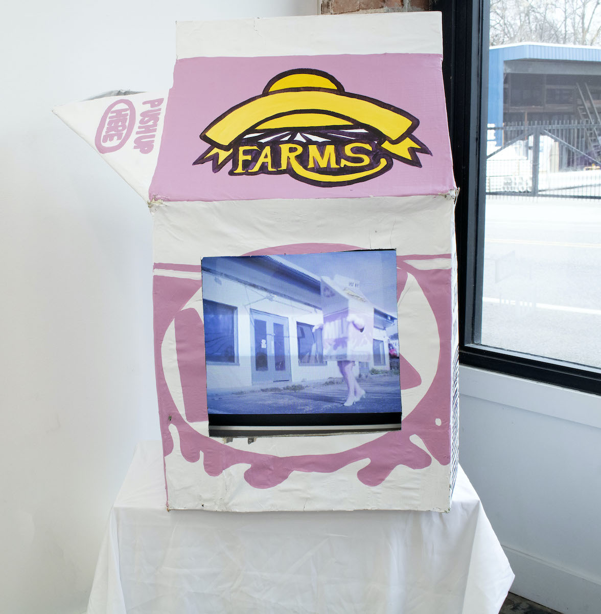 A single-serve pink and white and yellow cart on of milk with a photo pasted on it of someone in a milk-carton costume