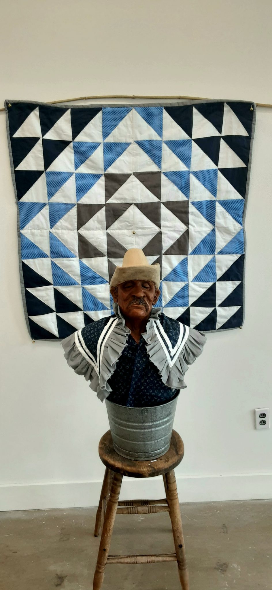 An artifact of a middle-aged man in front of a quilt