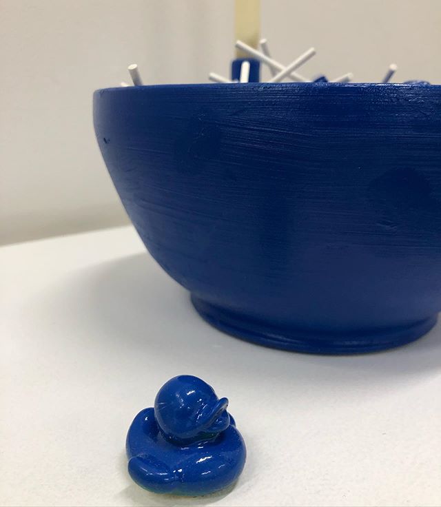 A large blue bowl next to a rubber duck painted blue