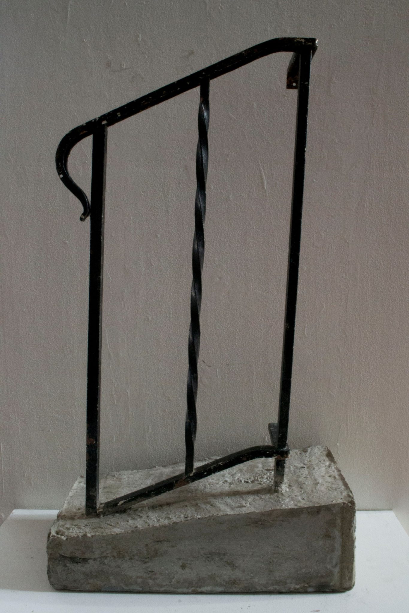 A photo of art from "Age Ingrained" showing a black handrailing on concrete