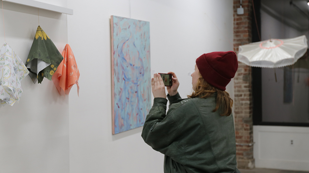 A patron taking a photo of an abstract painting at the display