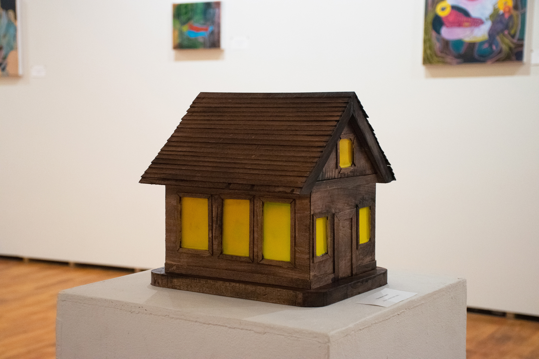 A model house made of white with the windows covered with yellow paint