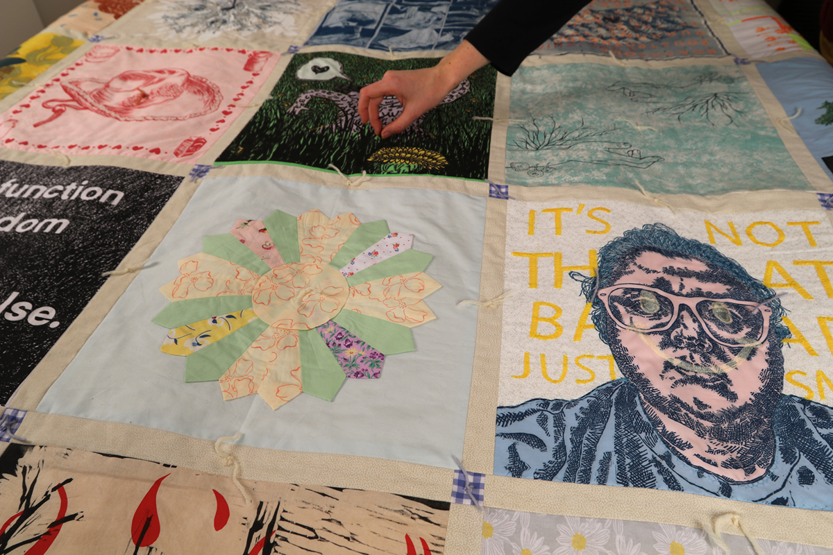 A zoomed in view of the quilt, featuring squares of different artwork