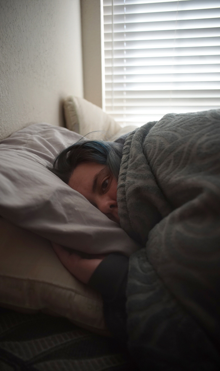 Photo of a woman in bed with covers up to her nose