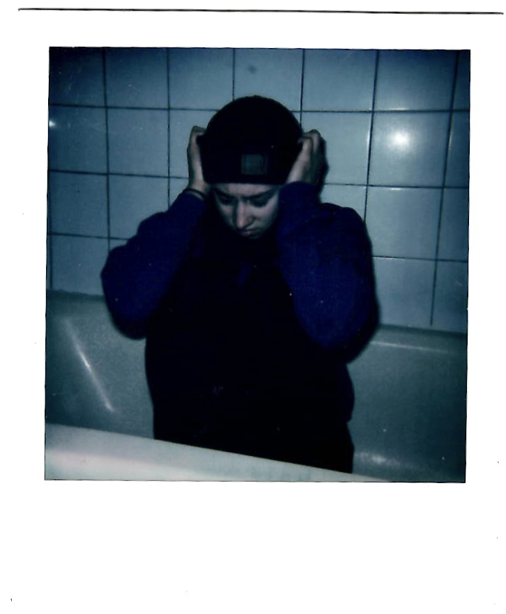 A photo of a person sitting in a bathtub looking depressed with their hands on the side of their head