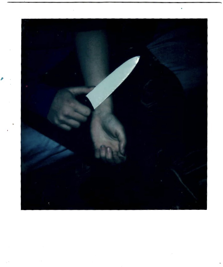 A person holding a knife to their wrist