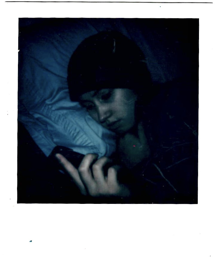 A depressed person in bed looking at their phone