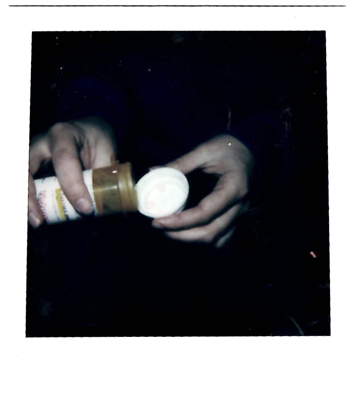 A close up photo of hands taking pills out of a bottle