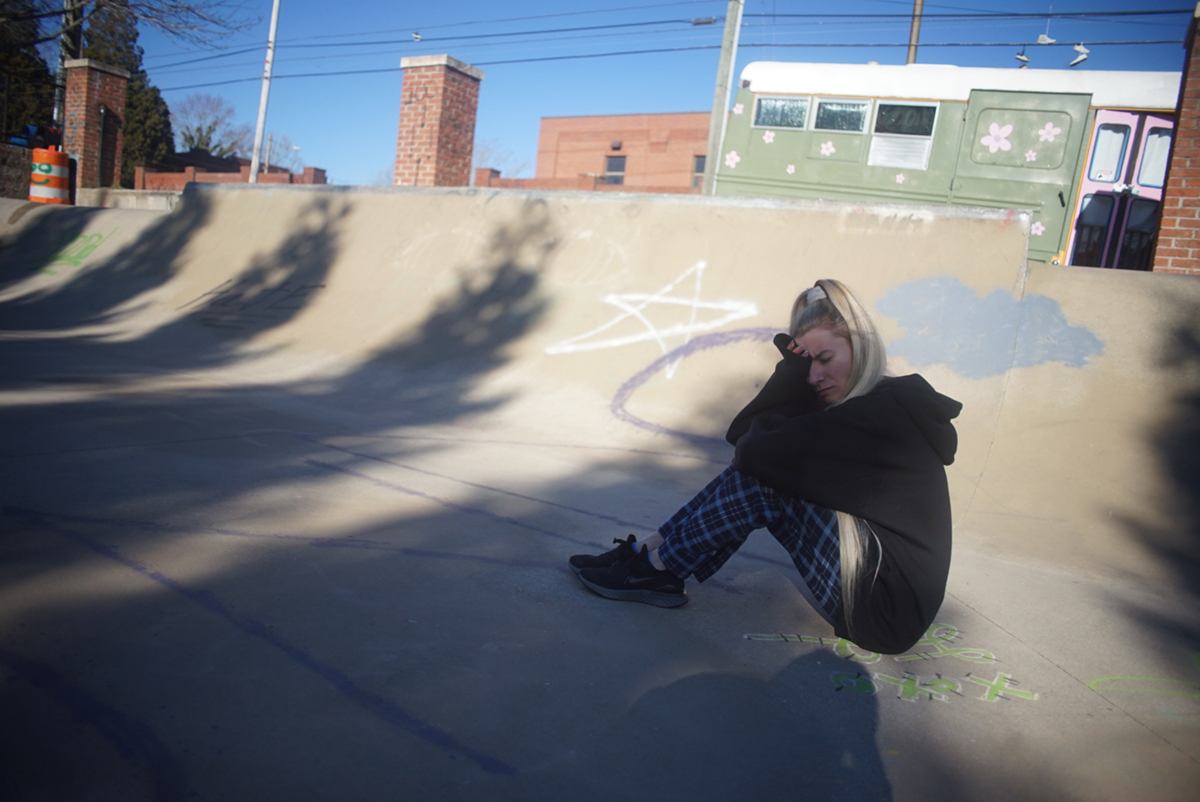 A young blonde woman sitting in a skate park
