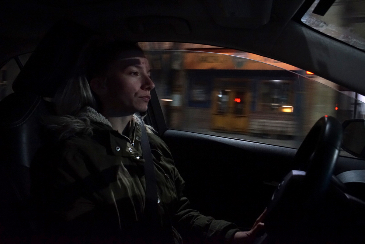 A person sits in a car at night
