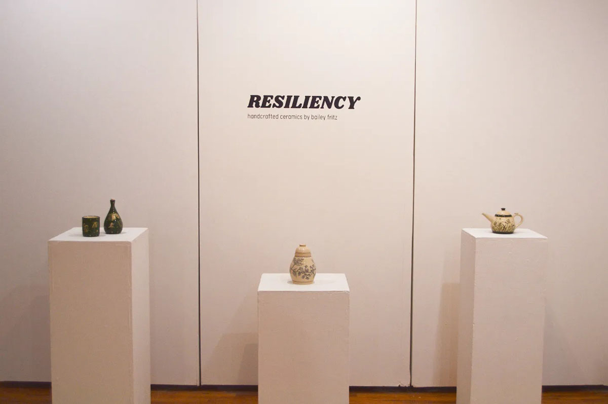 Photo of ceramic installation with text on the wall that reads "Resiliency: handcrafted ceramics by Bailey Fritz
