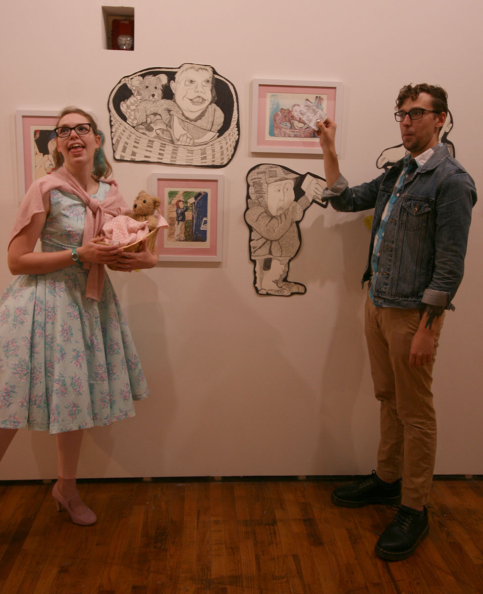 A man and a woman stand by the artworks as part of the "Baby Show" installation