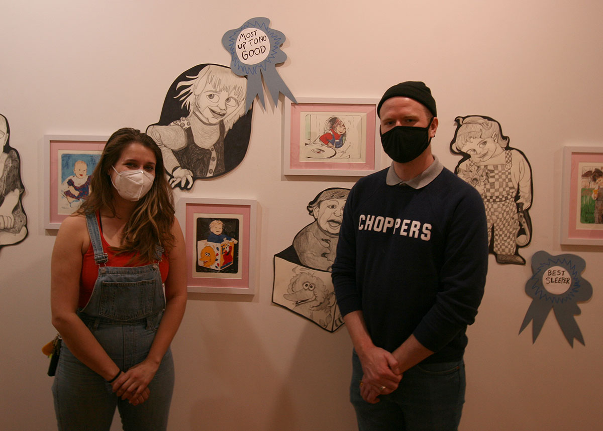 A masked man and woman posting for a photo by the "Baby Works" installation