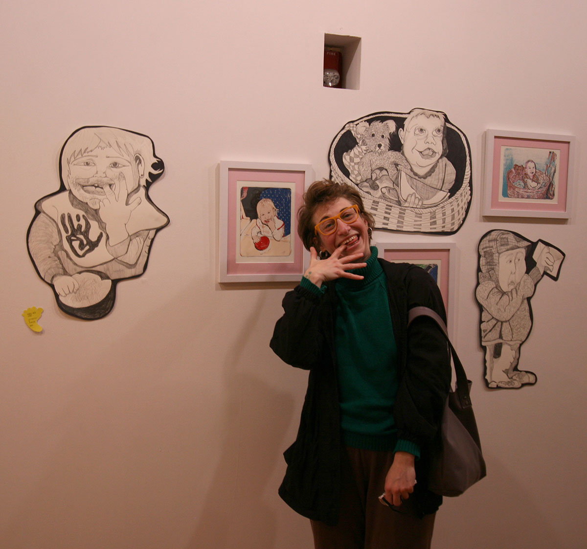 A patron posing for a photo in front of the "Baby Show" artowrks