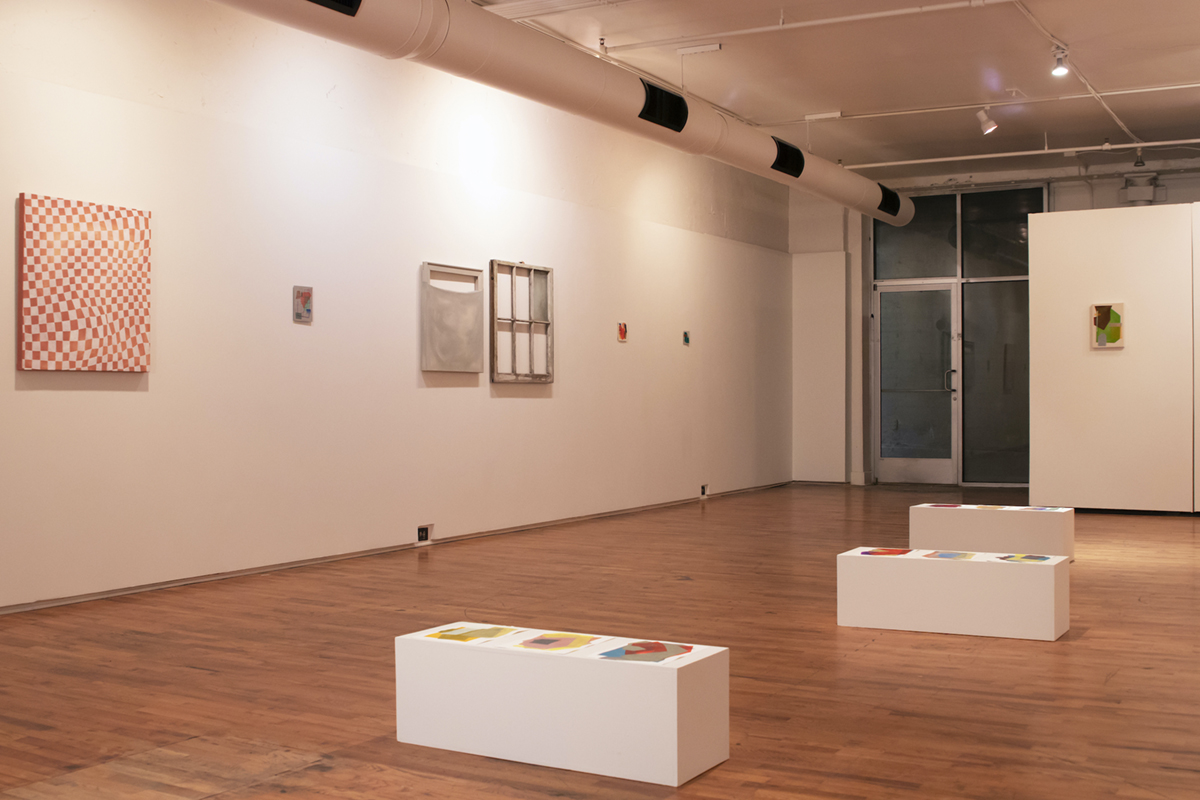 A zoomed out photo of the installation at the gallery, abstract paintings framed on the walls