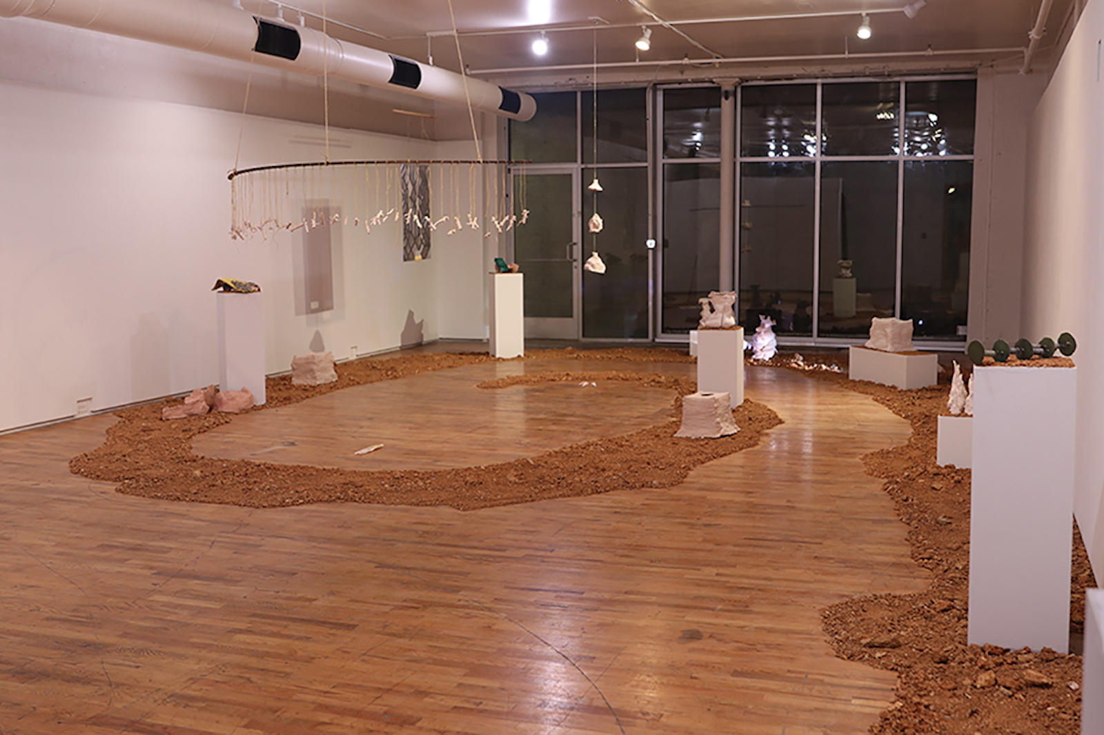 A zoomed out photo of the installation showing dirt and soil surrounding artifacts