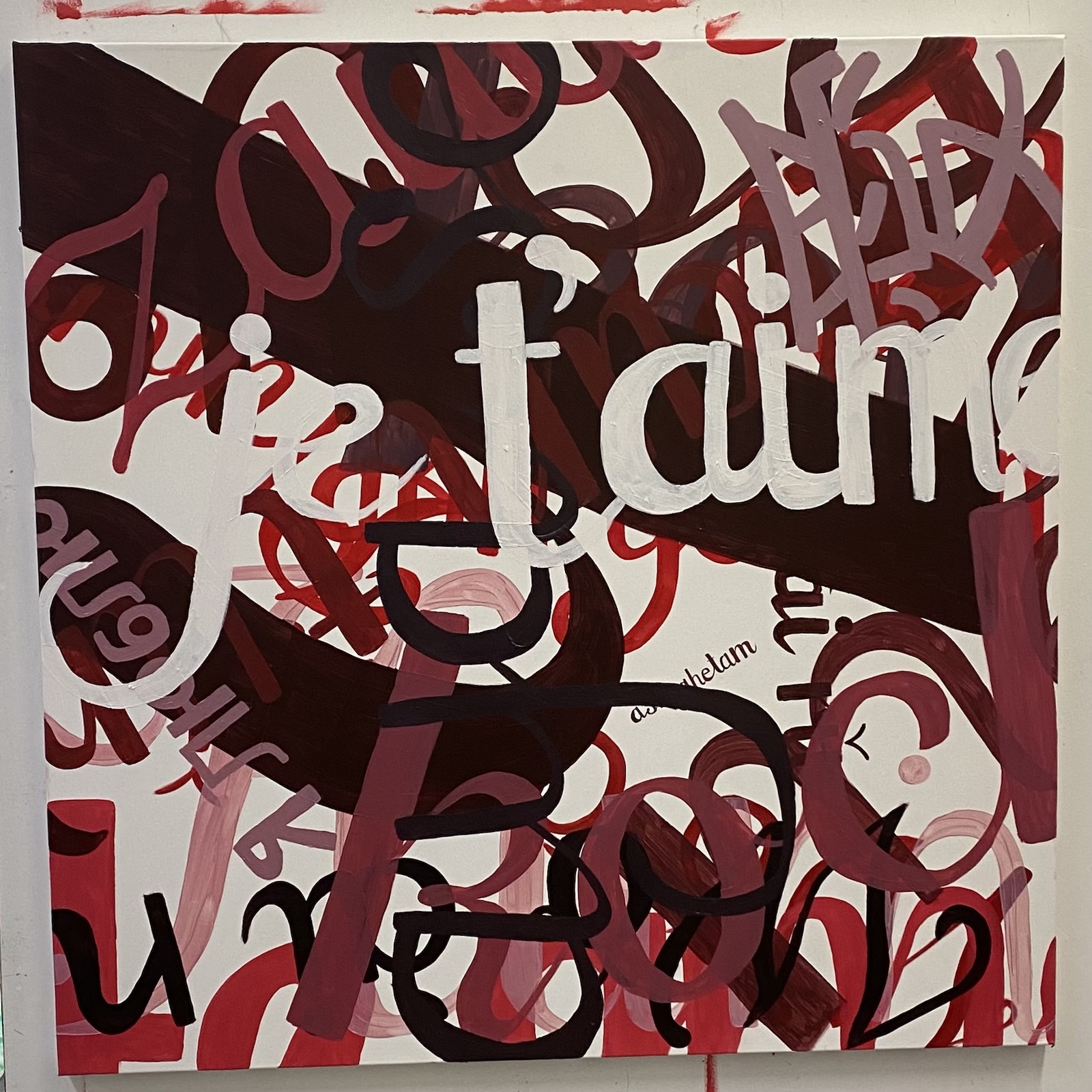 A painting with overlapping letters of white, brown, red, and pink