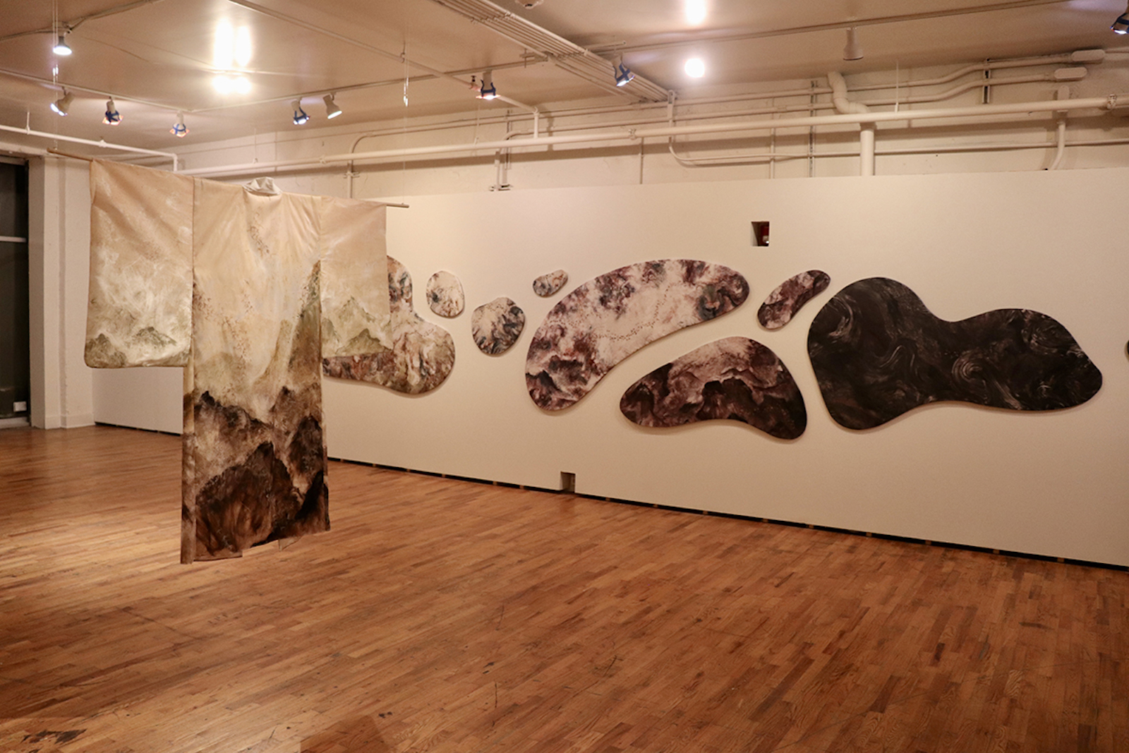 Large textured shapes on the wall, cloths hanging from the ceiling