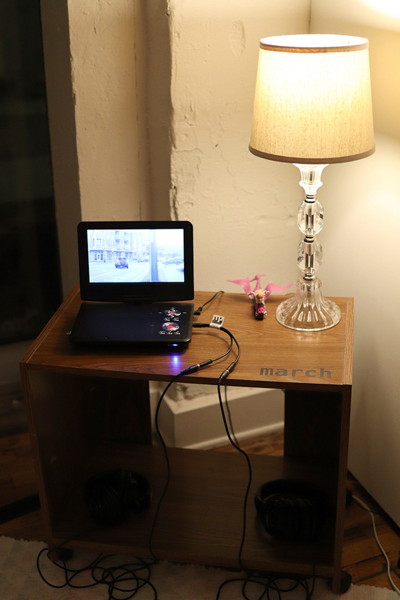 A small standalone dvd player on a table with a lamp