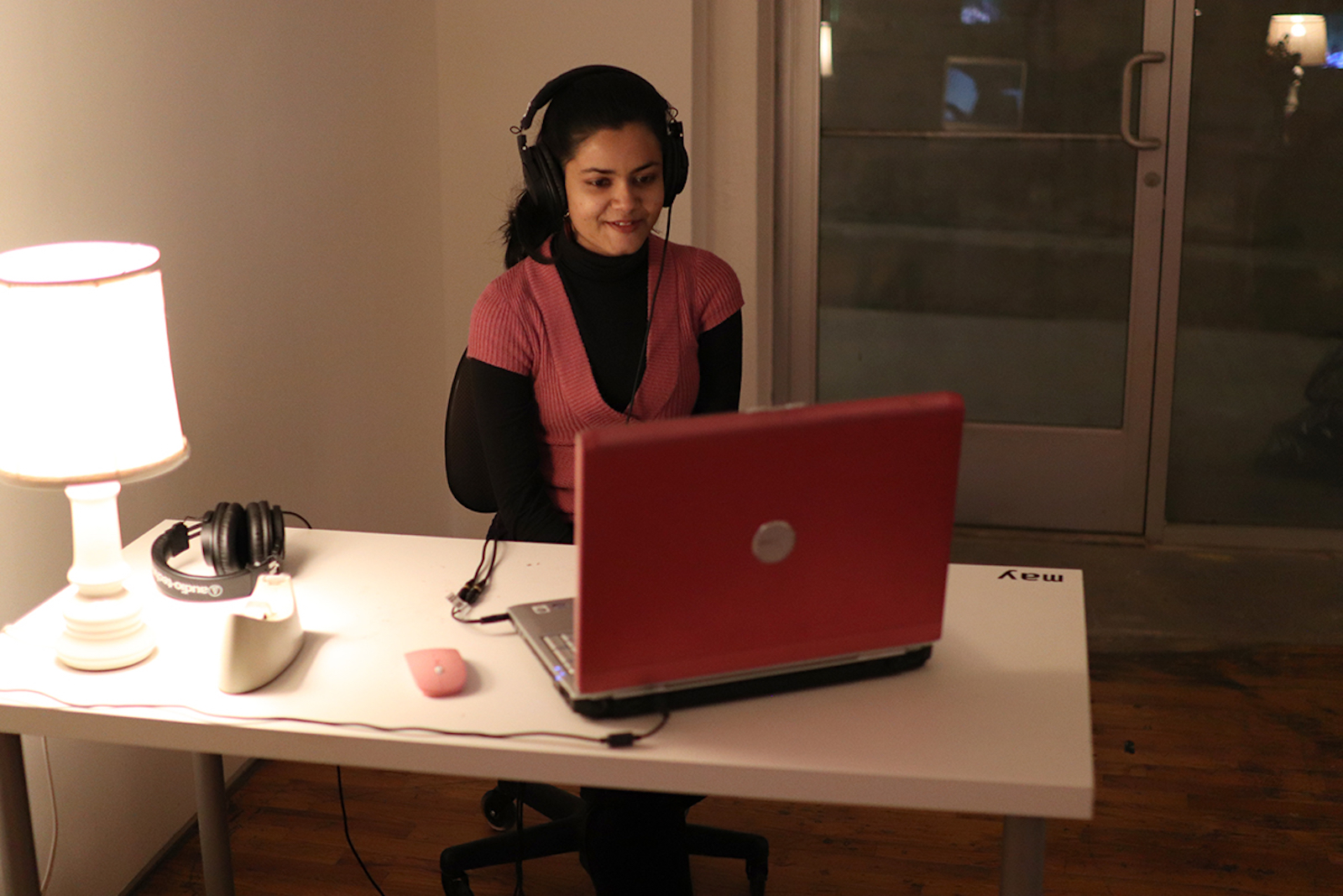 A woman watches a video on a red laptop with headphones on
