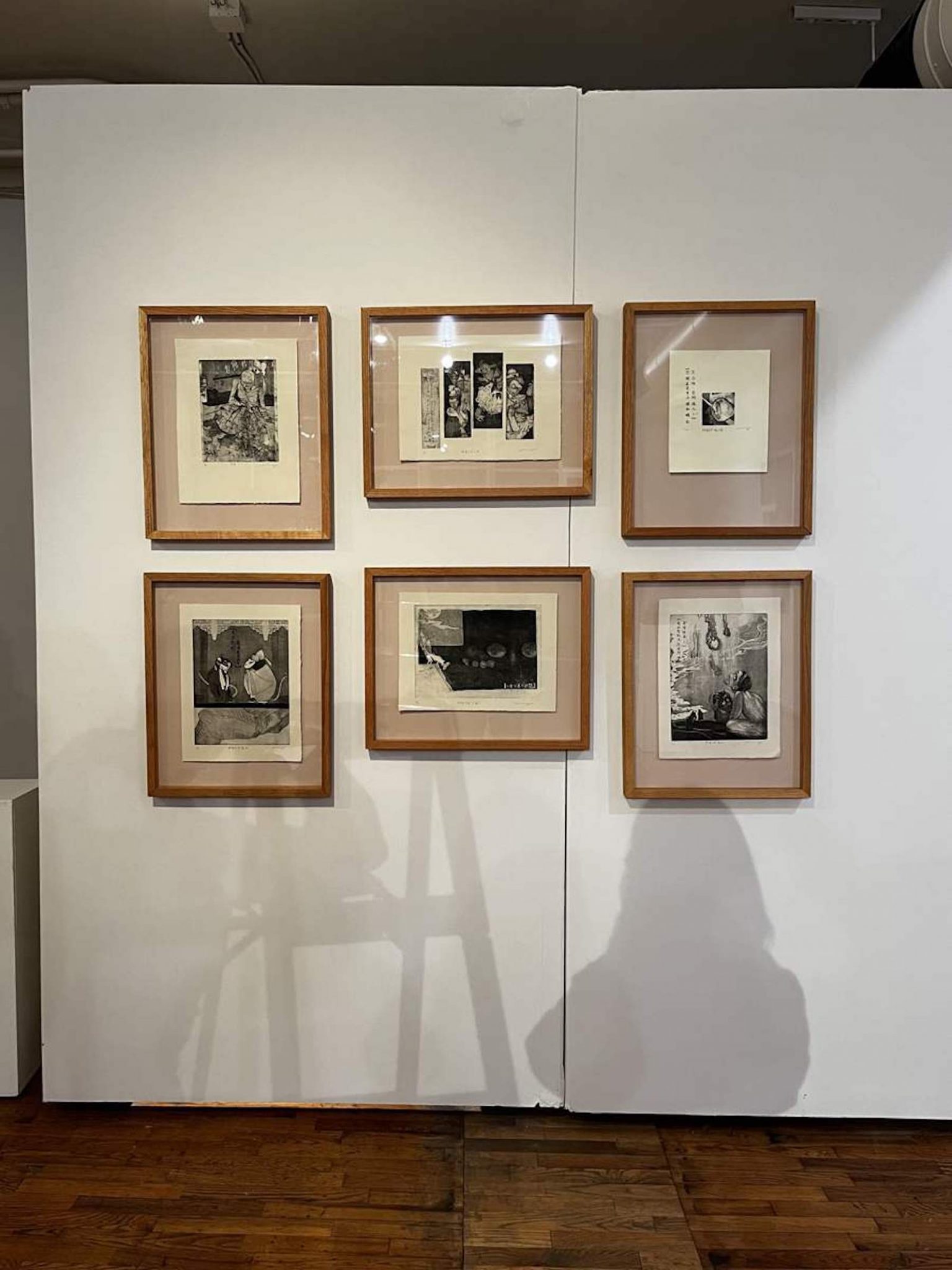 A zoomed out photo of a display of framed black and white artworks