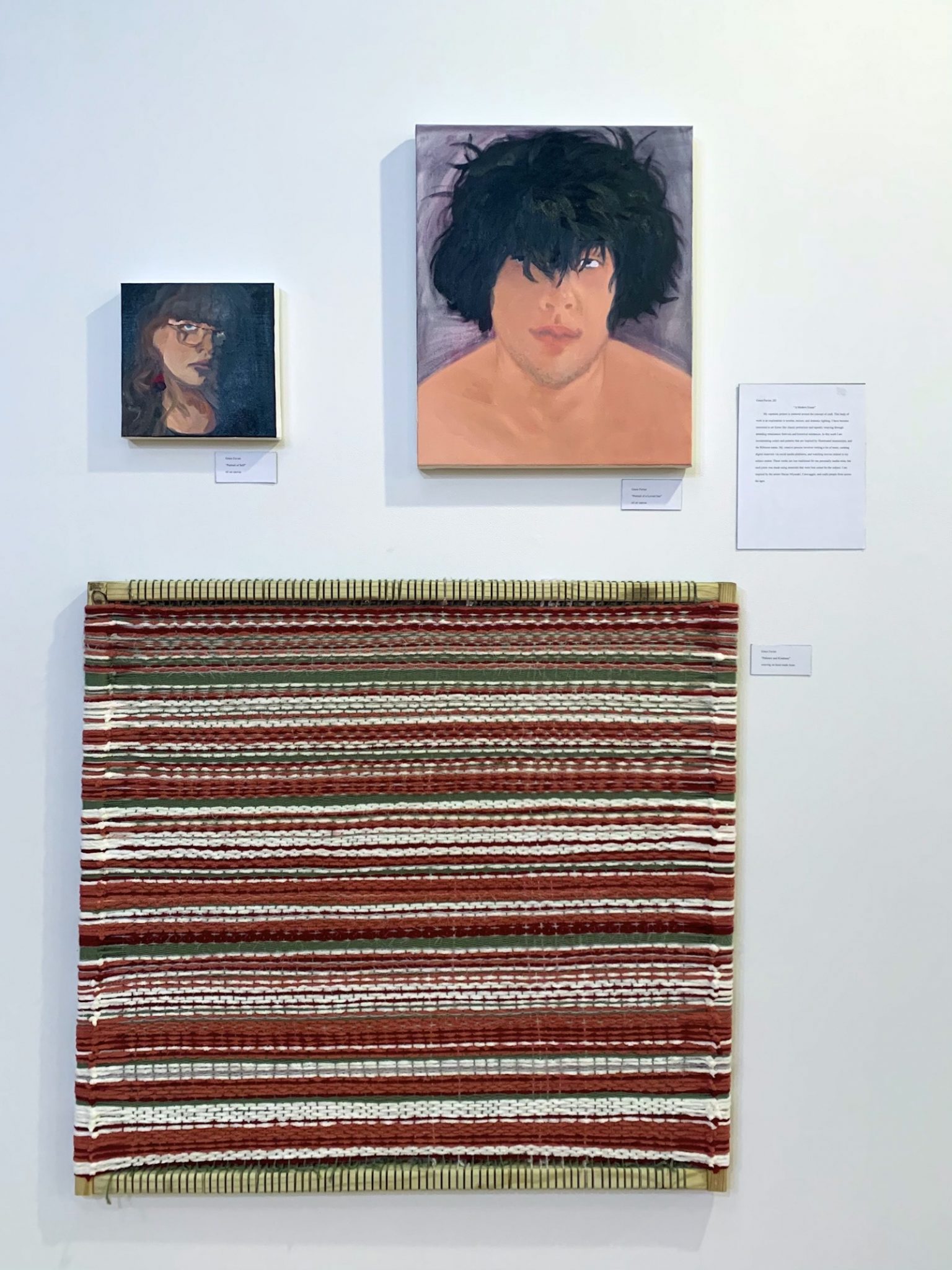 A tapestry blanket below two portrait paintings