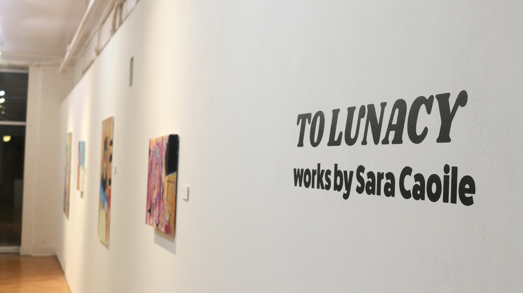 Gallery wall with To Lunacy vinyl title and paintings.