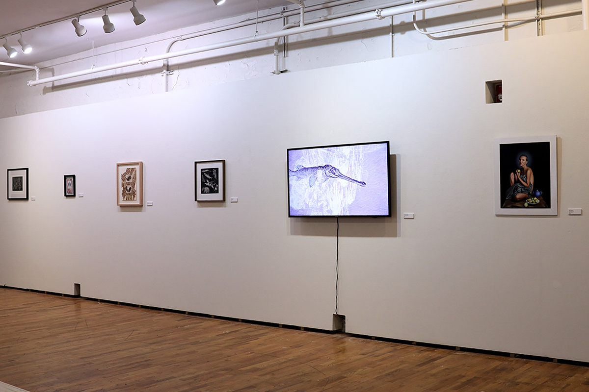 Gallery with framed paintings and prints with a television monitor showing an animation frame.
