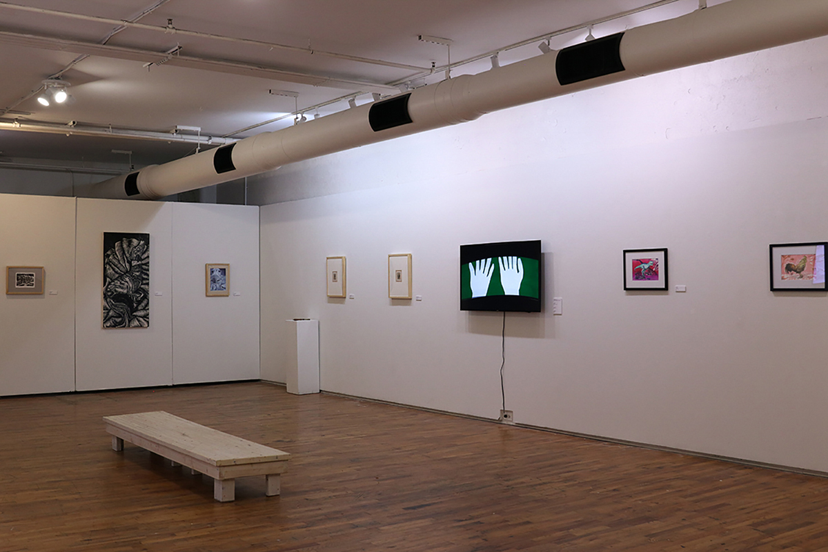 Gallery with framed paintings and prints with a television monitor showing an animation frame.