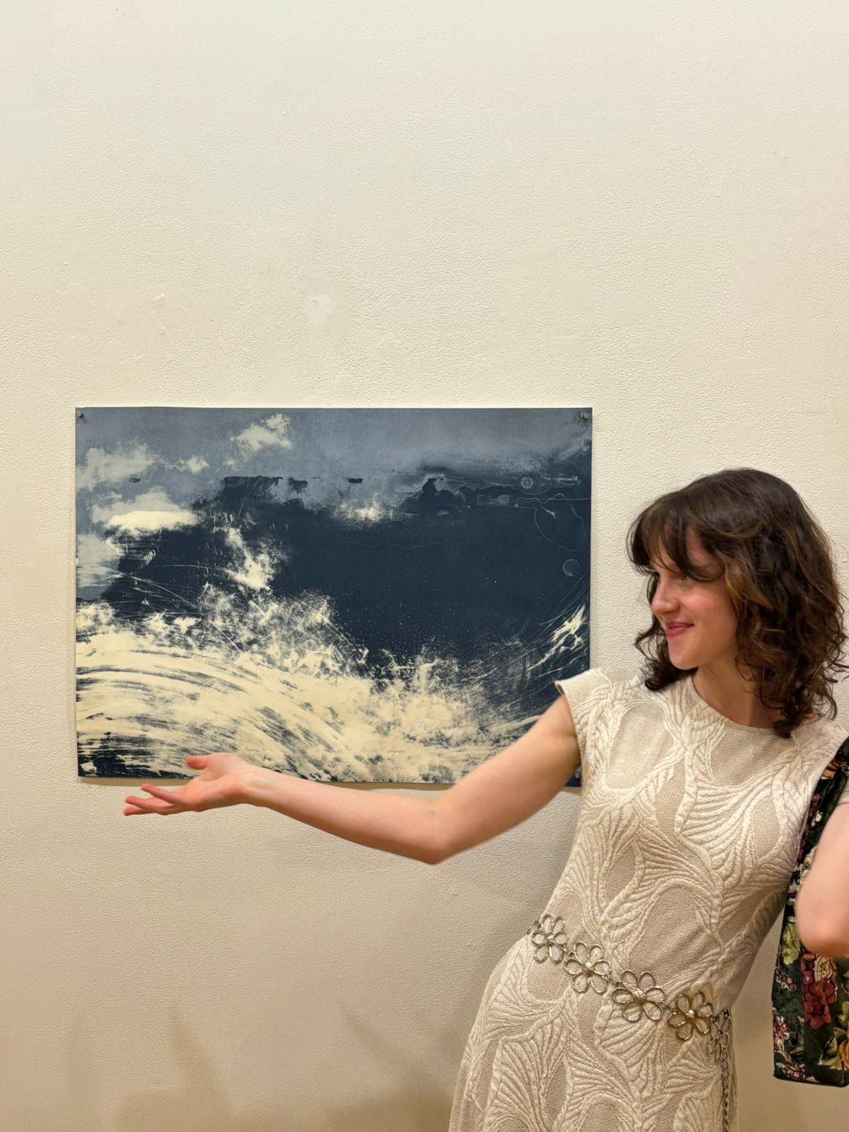 Basia Skałecka wearing a white dress standing next to a blue and white abstract print on paper.
